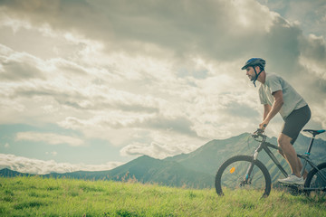 Fototapeta na wymiar Young athletic man riding bike in sunny day in mountain