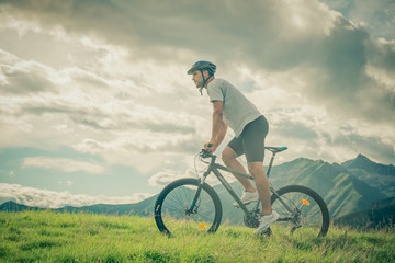 Fototapeta na wymiar Young athletic man riding bike in sunny day in mountain