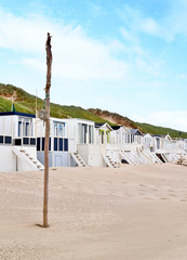 Beach huts or houses and blue sky. Multicolored beach bathing huts with white sand and clear blue sky. Beach scene with copy space. Side view of beach huts in a row.