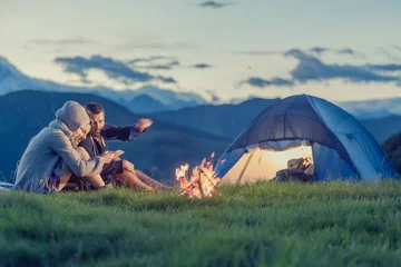 Foto auf Acrylglas Sport Drei Freunde campen mit Feuer auf dem Berg bei Sonnenuntergang