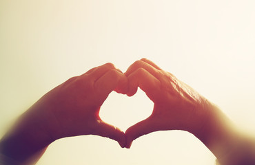 Fototapeta premium image of hands in the form of heart against the sunset sky