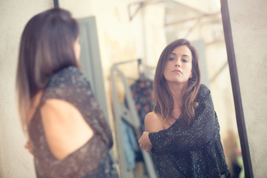 Young woman looking in the mirror portrait in a shop