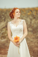 Fototapeta na wymiar Beautiful red haired bride on the sunflowers field background.