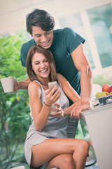 Young couple have breakfast with smartphone in the kitchen in sunny day