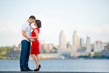 Happy young couple embraces against the city