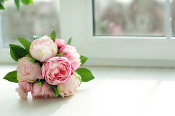 bouquet of peonies lies on a windowsill