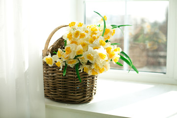 daffodils in a wicker basket sitting on the windowsill