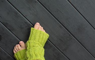 Children's legs in green socks on gray wooden floor