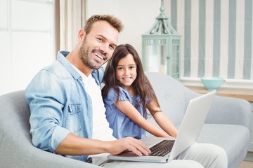 Portrait of happy father and daughter using laptop