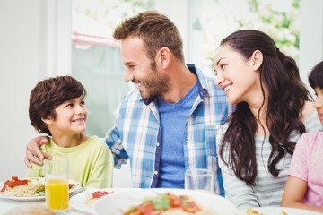 Smiling parents looking at son at dining table 