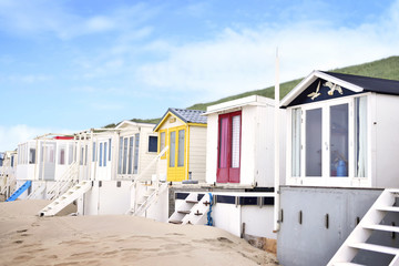 Beach huts or houses and blue sky. Multicolored beach bathing huts with white sand and clear blue sky. Beach scene with copy space. Side view of beach huts in a row.