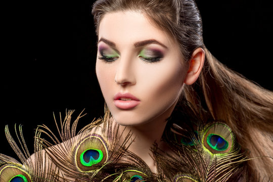 girl with bright  makeup and peacock feathe