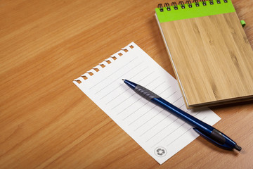 Blank note paper with pen on wood background