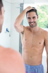 Obraz premium Handsome shirtless man smiling to a mirror