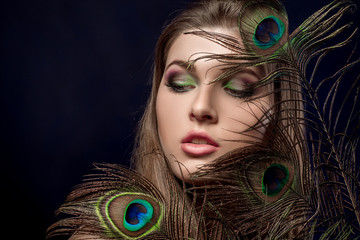 girl with bright  makeup and peacock feathe