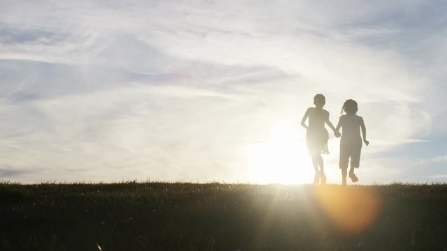 Silhouette children running towards the sunset