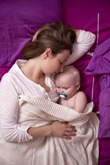 Mother with her baby sleeping in bed