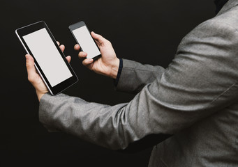 Man in suit with a pc tablet and a smartphone