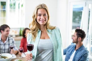 Smiling woman holding red wine glass with friends 
