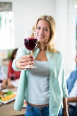 Smiling woman offering red wine glass 