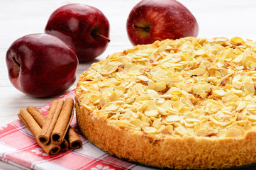 Apple pie with cream cheese and almond on white wooden background.