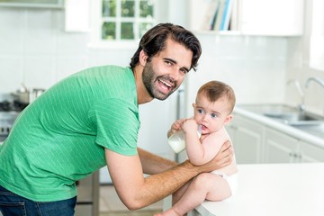 Happy father with son drinking milk at kitchen table