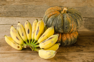 bananas and pumpkins on wooden table