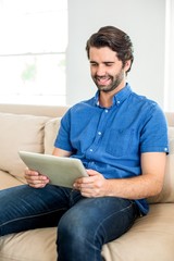 Man using digital tablet while sitting on sofa at home