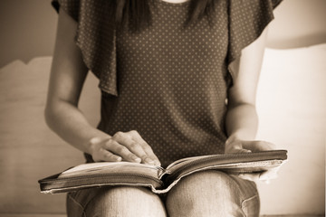 Closeup of a young woman reading a large bible, focus on the bib