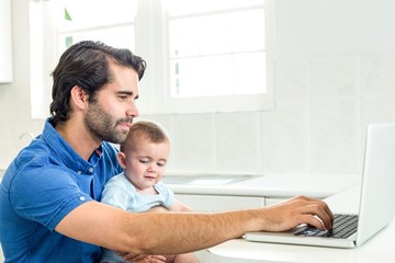 Man using laptop while sitting with son at home