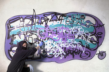 Girl paints a graffiti on the wall