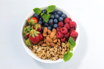 breakfast bowl with fresh berries, granola and almond, top view
