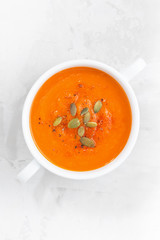colorful pumpkin cream soup on a white background, top view
