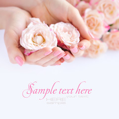 Hands of a woman with pink manicure on nails and roses against white background