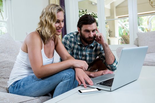 Smiling couple looking at laptop on table