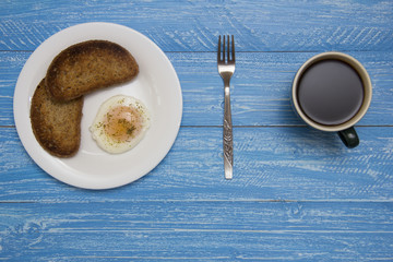 poached egg with two toasts and coffee on rustic background