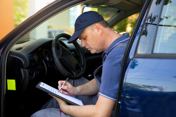 Portrait of a mechanic at wоrk writing on clipboard