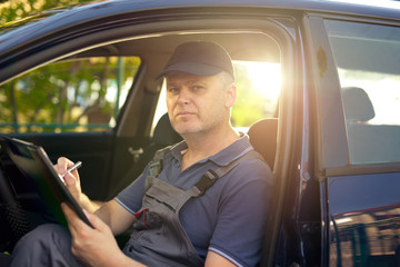 Portrait of a mechanic at wоrk writing on clipboard