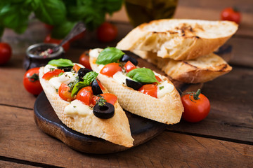Bruschetta with tomatoes, mozzarella, olives and basil pesto