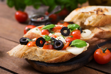 Bruschetta with tomatoes, mozzarella, olives and basil pesto