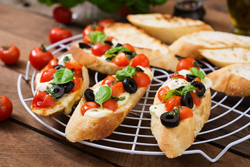 Bruschetta with tomatoes, mozzarella, olives and basil pesto