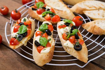 Bruschetta with tomatoes, mozzarella, olives and basil pesto