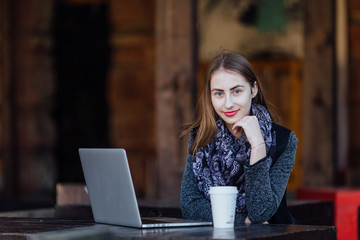 Young girl sitting behind the cafe on her laptop