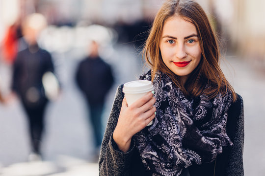Young girl walking on the street with cup of hot coffee
