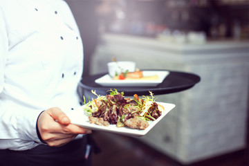 Waiters carrying plates with meat dish at a wedding.