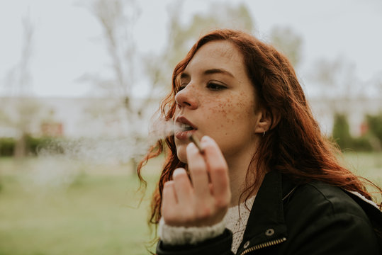 Redhead teen woman smoking in the forest