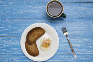 poached egg with two toasts and coffee on rustic background