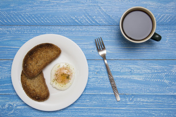 poached egg with two toasts and coffee on rustic background