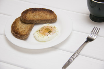 poached egg with two toasts and coffee on rustic background