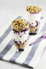 Useful dessert of granola, yogurt and blueberry in glass on a white background